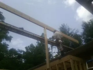 Carpenter setting a ridge beam over a new addition frame — Ice Dam Removal by Roofing Brothers in White River Junction