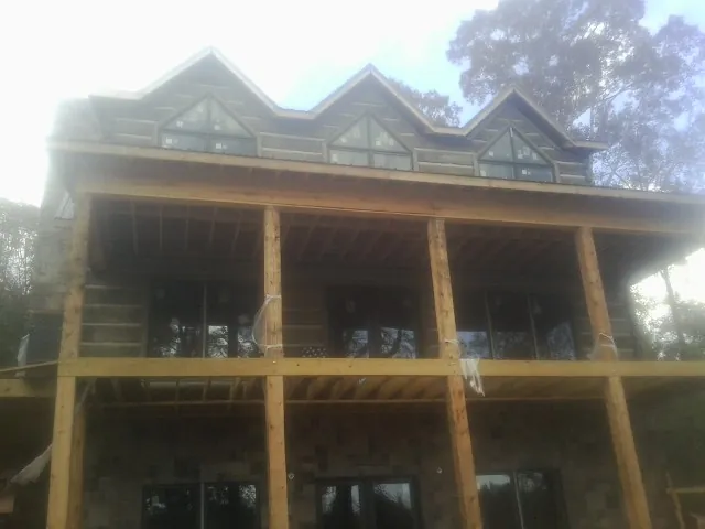Dormers and porch framing on a large log home under construction — Roof Coating work by our crew in White River Junction