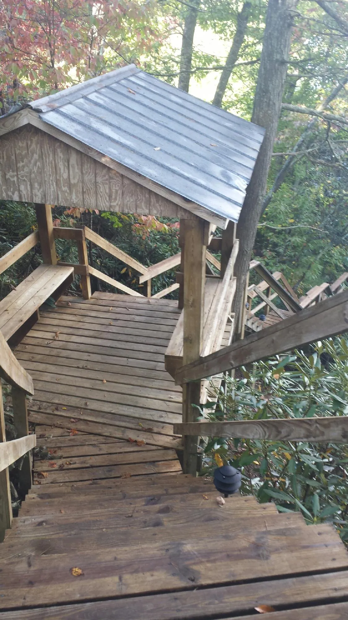 Metal roofed shelter over wooden steps on a wooded walkway — Skylight Repair & Installation work by our crew in White River Junction